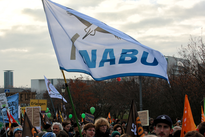 Eine große NABU-Fahne weht im Wind auf einer Demonstration